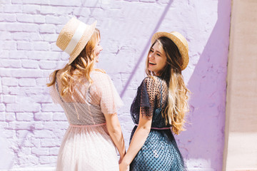 Outdoor portrait of shapely ladies in trendy summer dresses having fun together in sunny day. ...