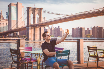 Tourist handsome male model taking a selfie near a Brooklyn Bridge
