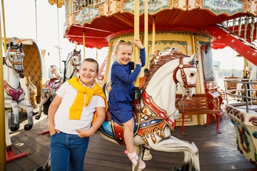 Obraz na płótnie Canvas little children brother and sister having fun on the carousel