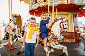 little children brother and sister having fun on the carousel