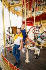 little children brother and sister having fun on the carousel