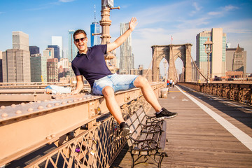 Tourist male model posing in front of Brooklyn Bridge
