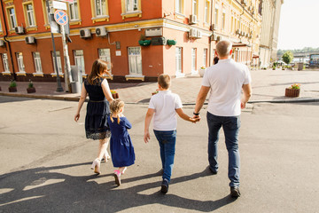 Obraz premium young family dad mom son and daughter are walking the street in the park at sunset and having fun