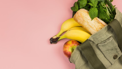 Zero waste and free plastic concept. Fruits, bread, herbs in a textile bag on pink background.16х9 banner format. Copy space.
