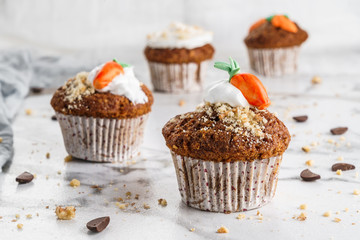 Easter cupcakes or muffins with cream and carrot candy on light marble background. Holiday cake celebration, delicious dessert, close up