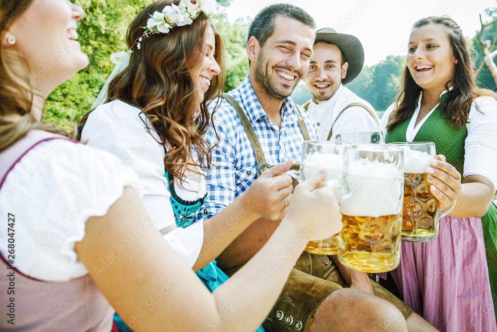 Wall mural Five friends, men and women, having fun on Bavarian RIver and clinking glasses with beer