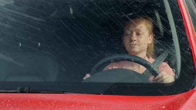 Girl driver drives a car when it rains on the street. Woman driving a auto.