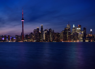 Twilight and Toronto city skyline with lights on highrise towers reflected Lake Ontario