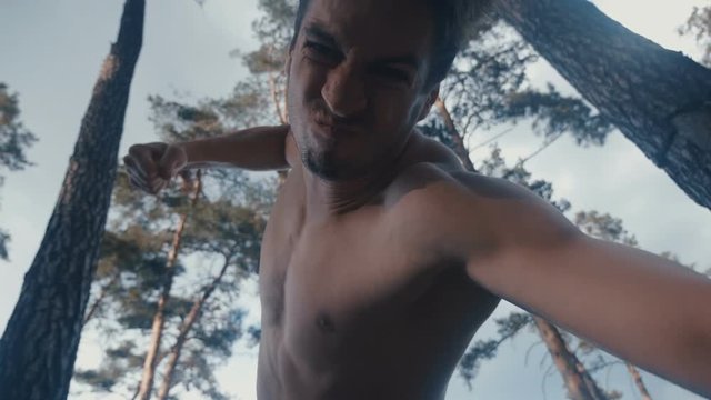 Aggressive shirtless man brutally beats lying opponent outdoor at forest. Knocking out debts.