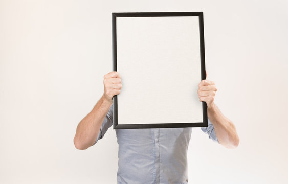 Unknown man wearing business shirt holding blank picture frame infront of his face