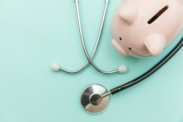 Medicine doctor equipment stethoscope or phonendoscope and piggy bank isolated on trendy pastel blue background. Health care financial checkup or saving for medical insurance costs concept