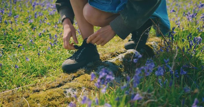 Young woman tying her shoes in meadow