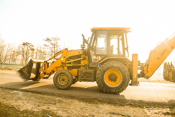 yellow front loader bulldozer in the village field going to construction site, day time, sunlight - background - image
