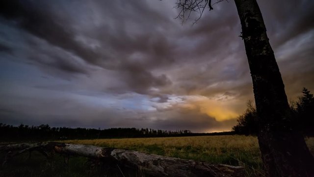 Night on the prairie with storm clouds and northern lights and morning twilight, time lapse.