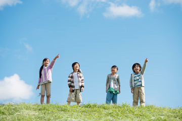 草原で空を見上げる小学生