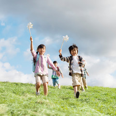 風車を持ち草原を走る小学生