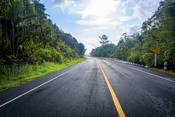 Fototapeta premium Asphalt road and mountains landscape under fog from rain with clouds