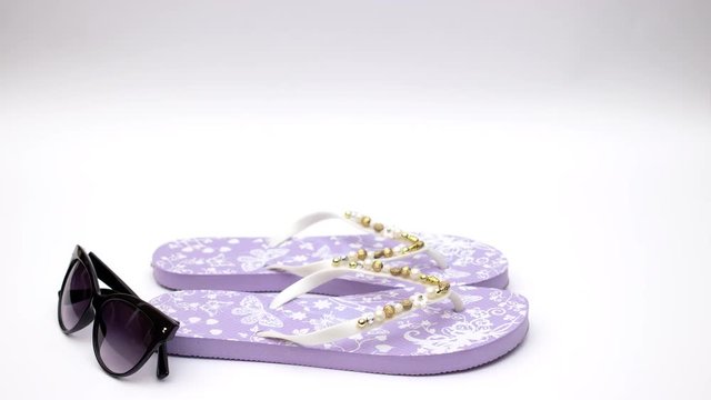 Purple slippers and sunglasses and sea shell on white background - Stop motion 