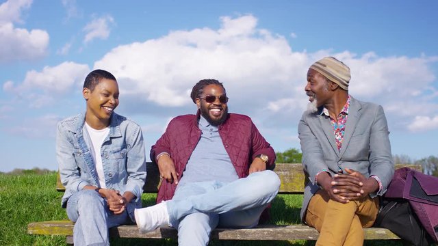 Diverse group of black people in conversation together on a park bench