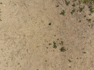 Close distance photo of sand with small pebbles twigs and grass detail.