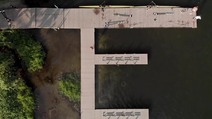 Aerial top down view passing a rowing dock and training facility in the city lake of Rio de Janeiro with rowers arriving and coming out of the water. Landing stage for canoe and peddling sports. - Powered by Adobe