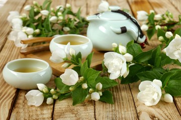 Jasmine tea.Green tea with jasmine flowers.green teapot and two cups of tea, jasmine branches on a wooden  background.Organic Natural Herbal Bio Tea