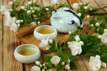 Jasmine tea.Green tea with jasmine flowers.green teapot and cups of tea, jasmine branches on a...