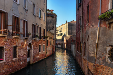 Fototapeta na wymiar Narrow canal among old brick houses. Venice. Italy.