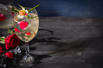 Sparkling cold water detox with rose and ice on the wood table there are rose, diferance glass and ice placed be side.