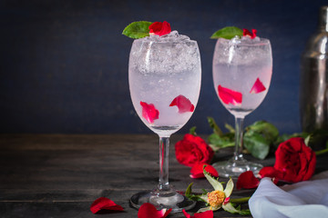 Sparkling cold water detox with rose and ice on the wood table there are rose, same object and cocktail shaker placed around.
