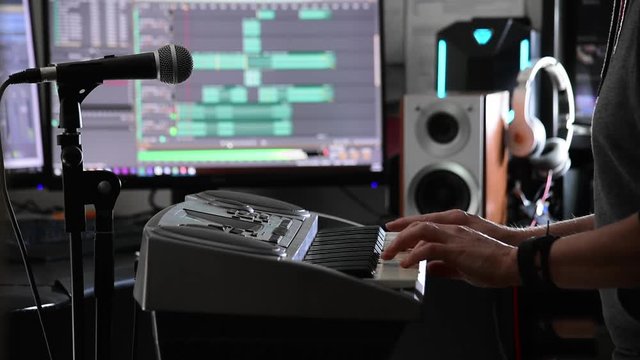 Musician plays keyboard in home recording with software shown on screens in background