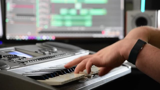 Shot of a musician's hands playing chords on a keyboard in a home recording studio