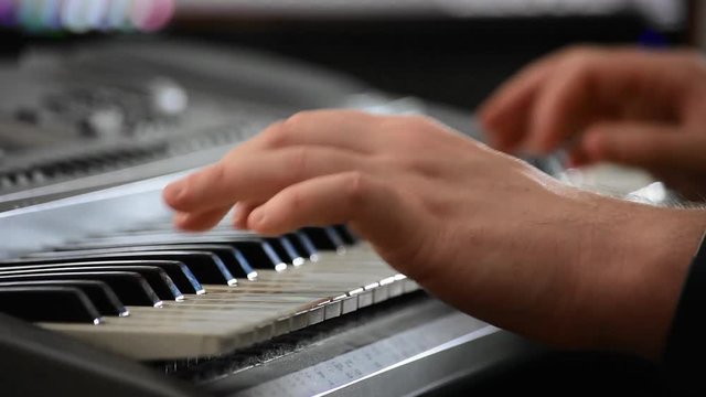 Close up of hands playing a keyboard in a home recording studio