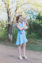 Mom gently holding infant girl offspring and standing on country road outdoors artistic photograph