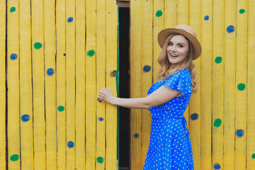 Young lone lady standing in front of a dwelling yellow wall opening door vintage romantic picture