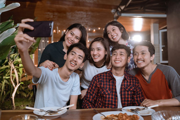 asian bestfriend group take selfie with smartphone while having garden party dinner together
