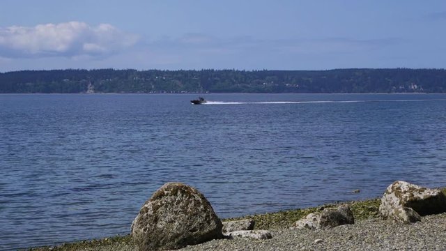 Small, nondescript fishing boat cruising past beach at Camano Island State Park, WA State. 10sec/24fps slow motion. Version 3
