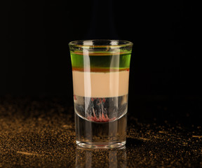 mixed alcoholic liquor with cinnamon in a shot glass isolated on a black background