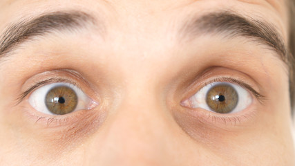 Close-up of a surprised emotional man with brown eyes looking into the camera.