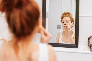 Obraz na płótnie Canvas Young redhead woman applying morning makeup