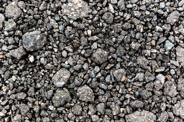 Rough black gravel surface road after rain.