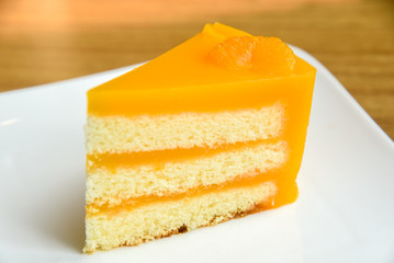 Orange cake in a white plate on wooden background ,  fruit cake