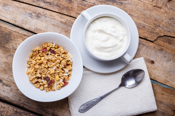 Healthy breakfast background. Muesli with yoghurt in bowl on wooden background
