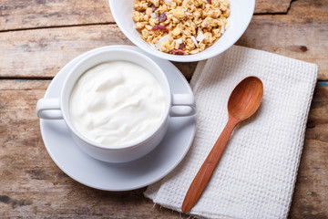 Healthy breakfast background. Muesli with yoghurt in bowl on wooden background