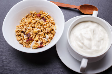 Muesli with greek yohurt in white bowl on slate background
