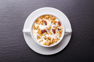 Muesli with greek yohurt in white bowl on slate background