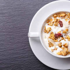 Muesli with greek yohurt in white bowl on slate background