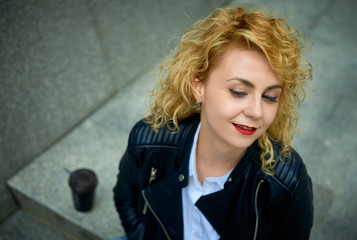 lifestyle curly blonde young woman enjoying the walk in the city and feels happy in the modern...