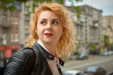 lifestyle curly blonde young woman enjoying the walk in the city and feels happy in the modern cityscape