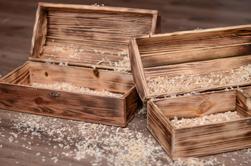 Two vintage wooden luxury gift boxes or caskets on wood background. Open box filled with natural raffia or sawdust